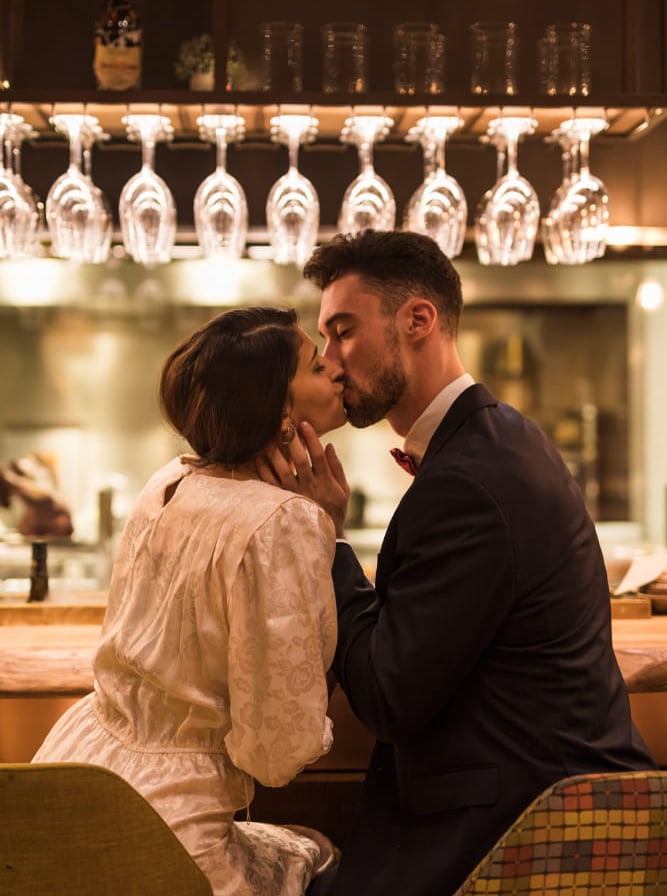 Sugar mommy and her sugar baby sharing a tender kiss in an upscale bar.