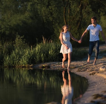 a sugar mommy and sugar baby holding hands and walking along a river