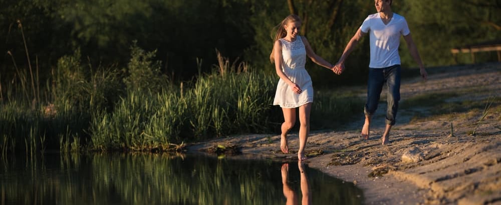 a sugar mommy and sugar baby holding hands and walking along a river